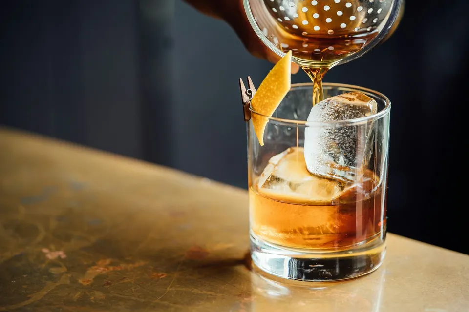 Whisky versé sur un gros glaçon dans un verre bas